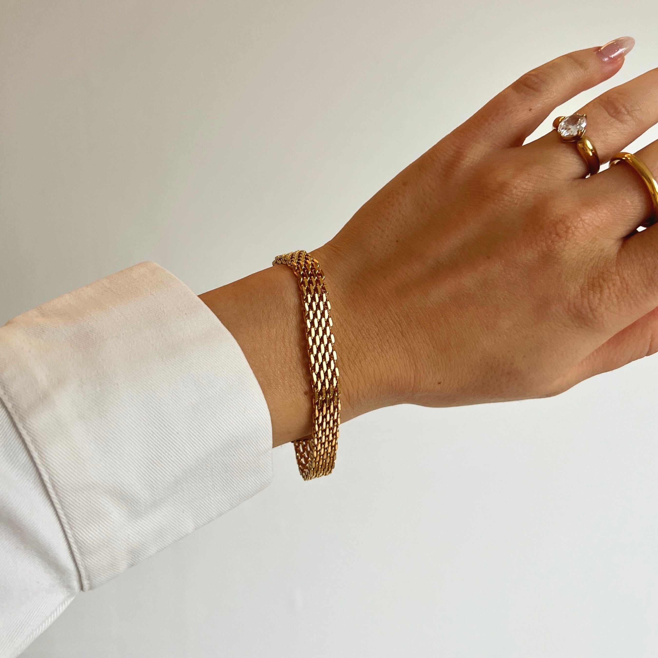 Aster Aurora Bracelet – brett guldigt nätlänkarmband i rostfritt stål med PVD-plätering i 18K guld, vattentåligt och allergivänligt.