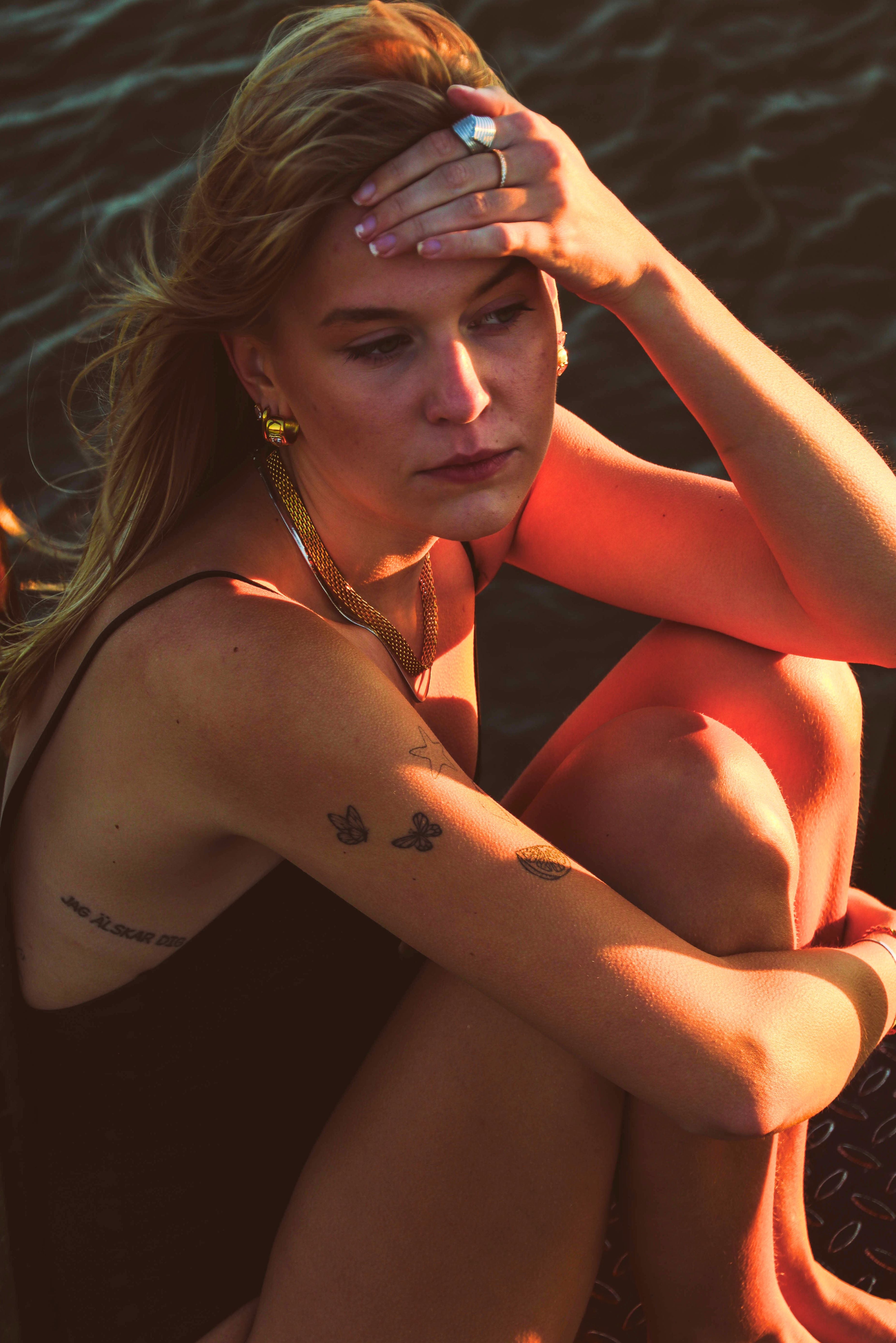 Modell bär Alora Avenue smycken – ringar, halsband och örhängen i rostfritt stål med PVD-plätering. Vattentåliga och allergivänliga smycken för hösten, designade att användas varje dag.