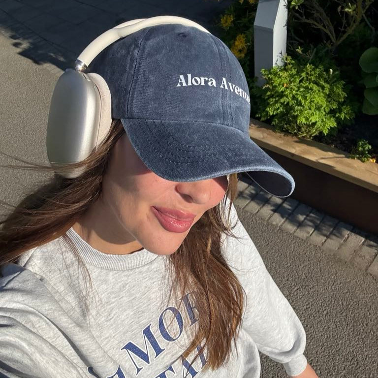 Marinblå Alora Avenue-keps med vit logga under en solig promenad – casual och tidlös stil.