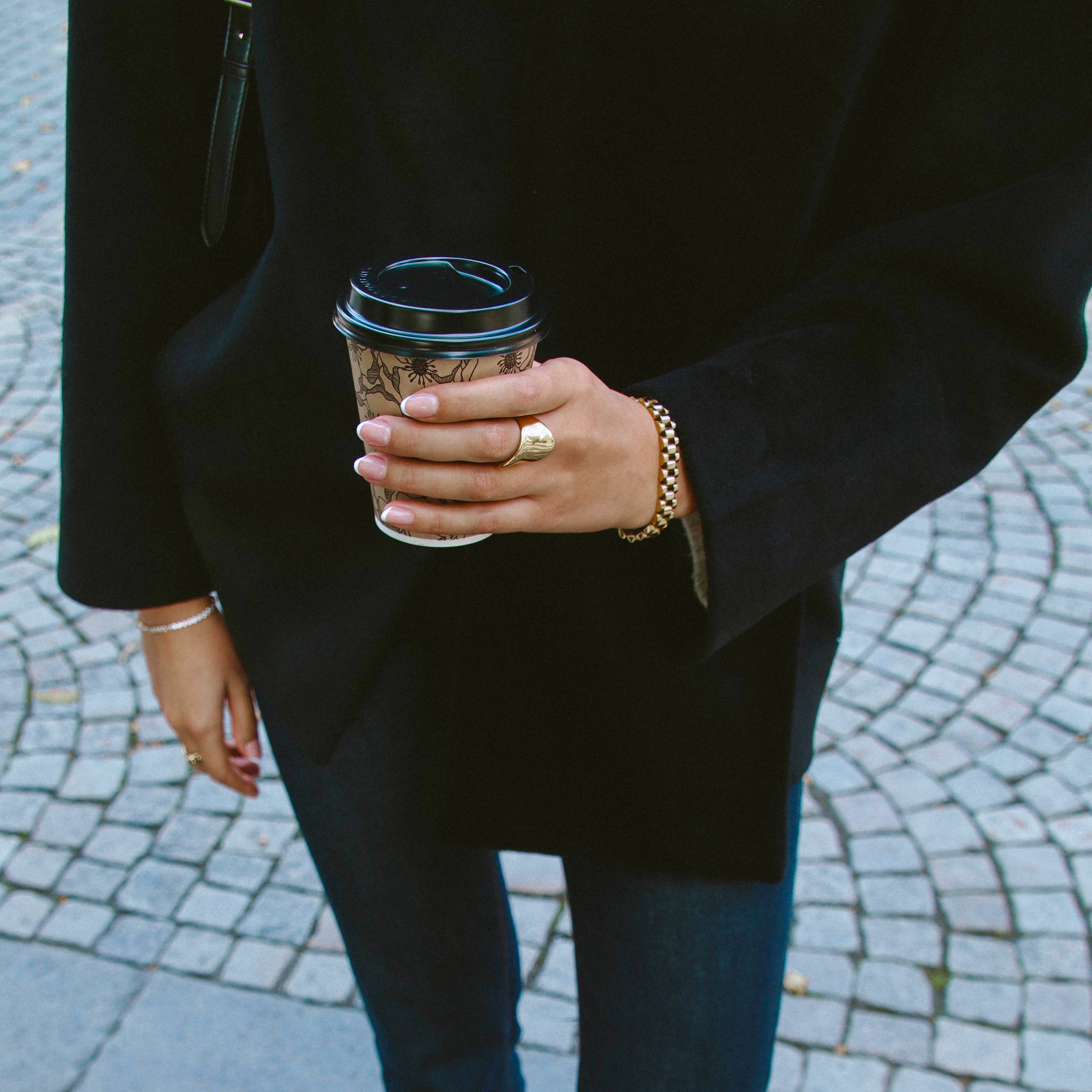 Analog Aria Wristband i guld på handled, stylat tillsammans med kaffe och höstoutfit. Elegant, vattentåligt och tidlöst armband från Alora Avenue.