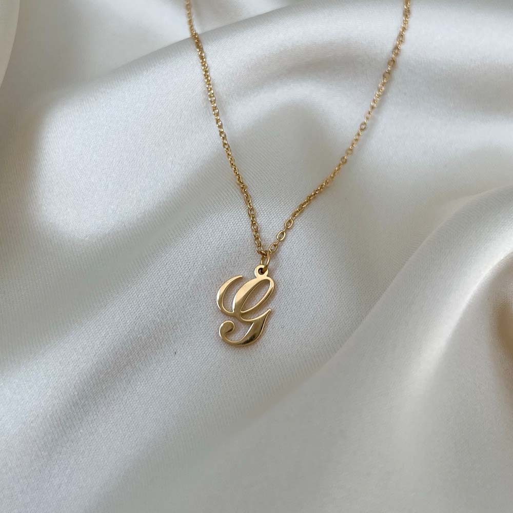 Stilfullt Alora Letter Necklace med bokstaven G, en tidlös detalj i 18K PVD-pläterat guld som är vattentåligt och allergivänligt.