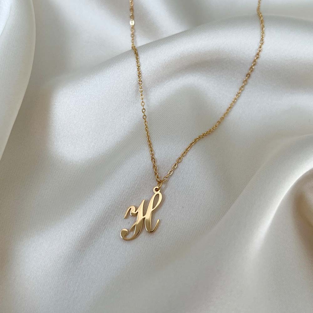 Alora Letter Necklace med bokstaven H i skrivstil, ett elegant halsband som kombinerar hållbarhet och personlig charm.