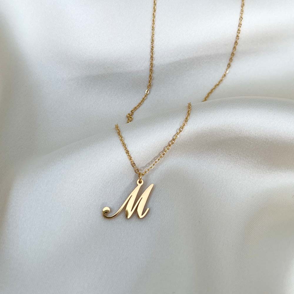 Alora Letter Necklace med bokstaven M, ett sofistikerat halsband i guld med personlig touch och vattentåligt material.