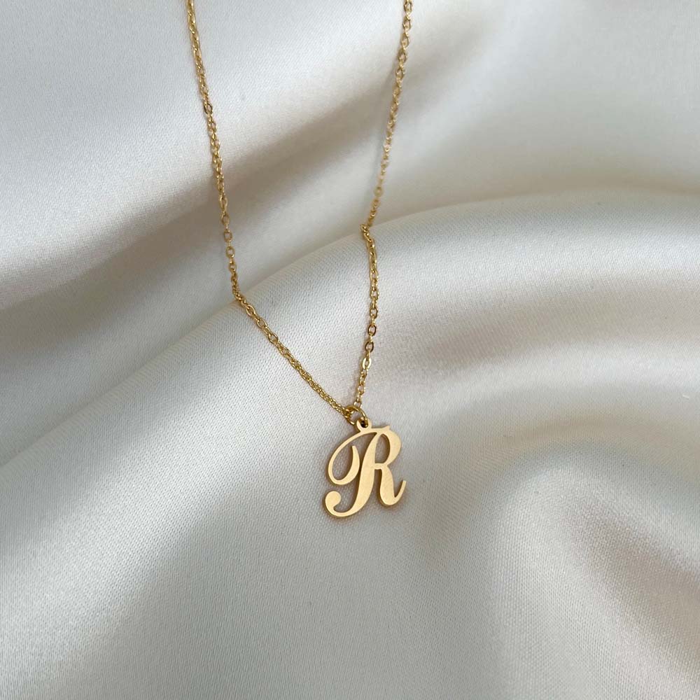 Alora Letter Necklace med bokstaven R i skrivstil, en perfekt accessoar som kombinerar elegans och hållbarhet.