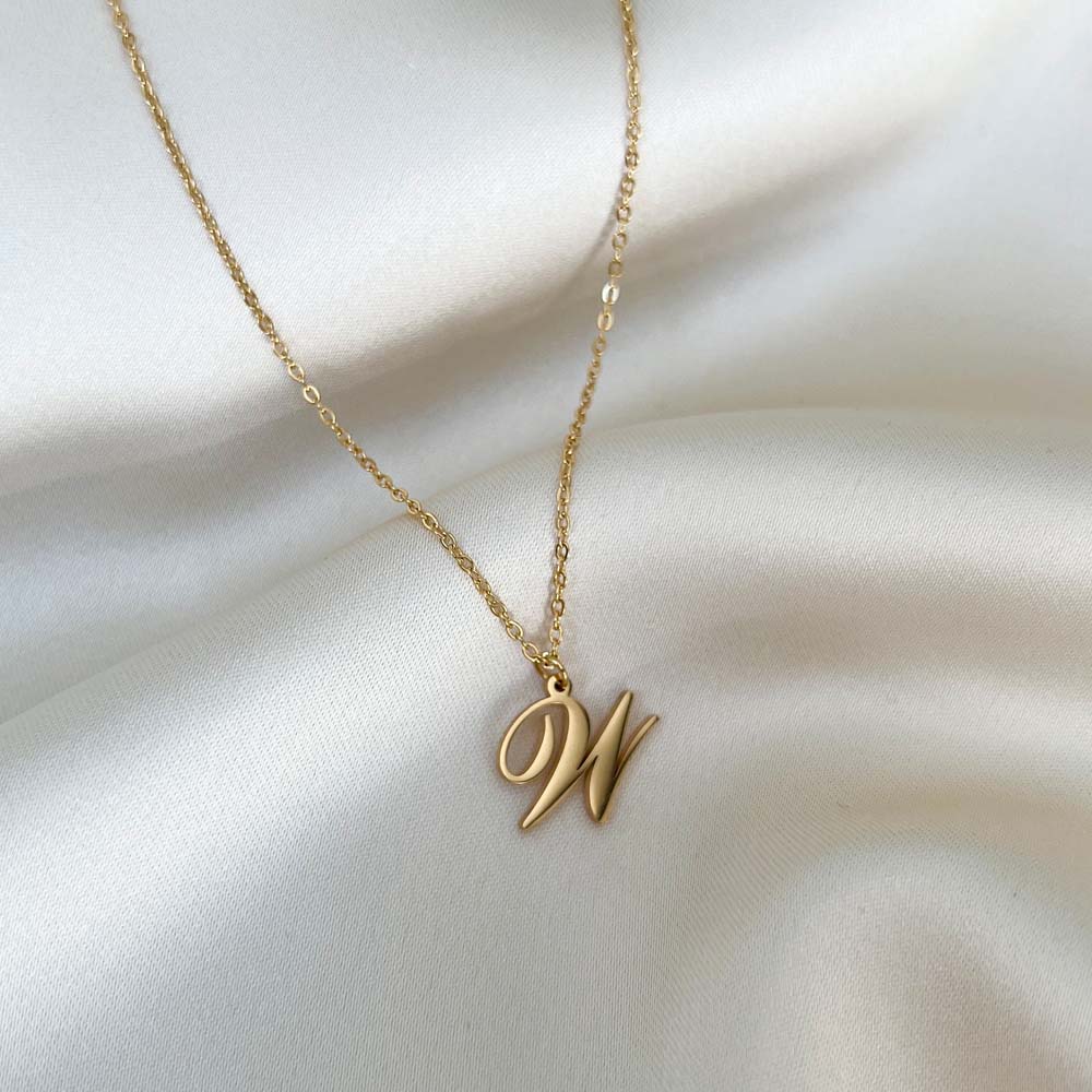 Alora Letter Necklace med bokstaven W i guld, ett tidlöst smycke med personlig charm och vattentålig finish.