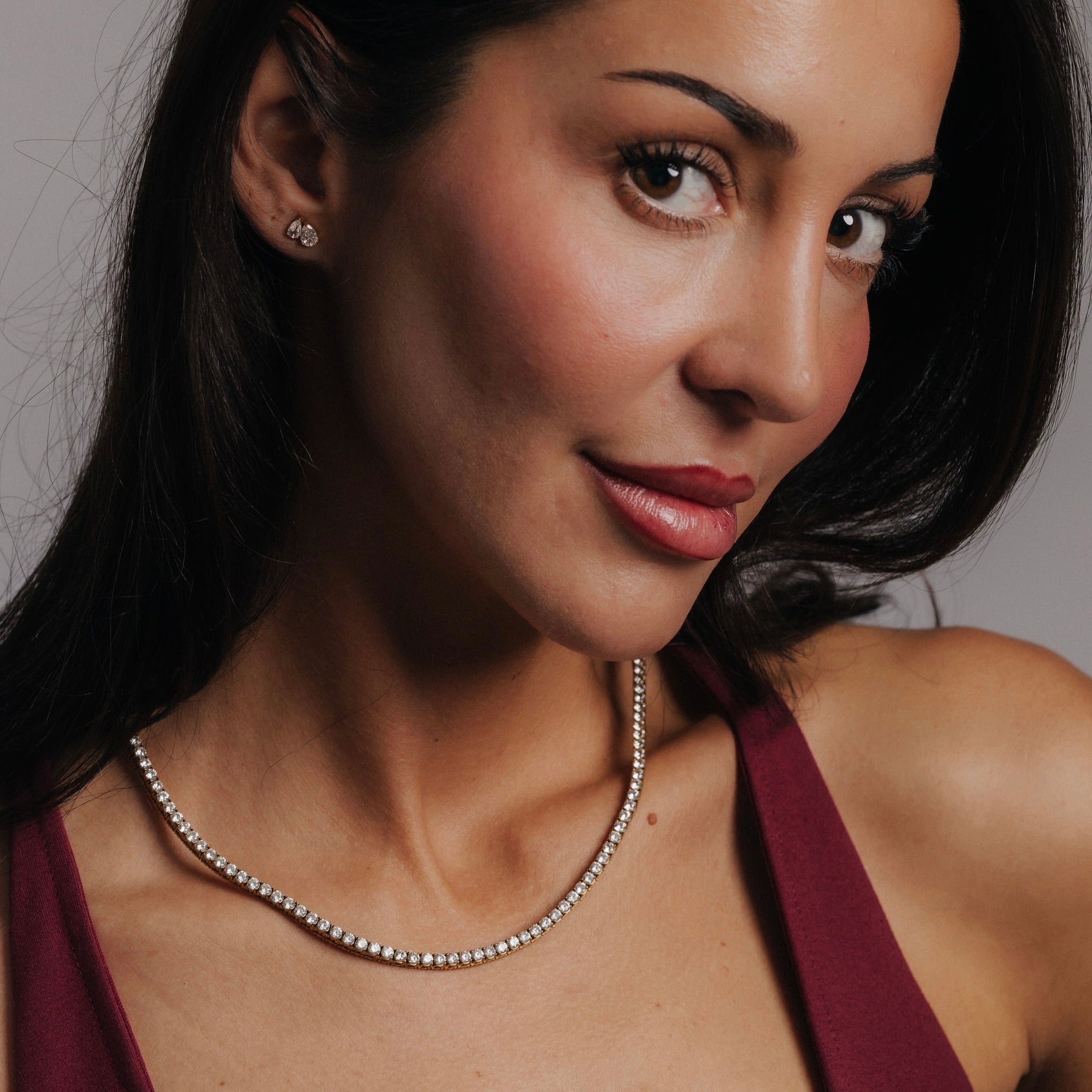 Kvinna bär Alora Avenue Amara Tennis Necklace i 18K PVD-plätering. Vattentåligt och nickelfritt halsband som gnistrar mot huden och förhöjer varje festlig look.