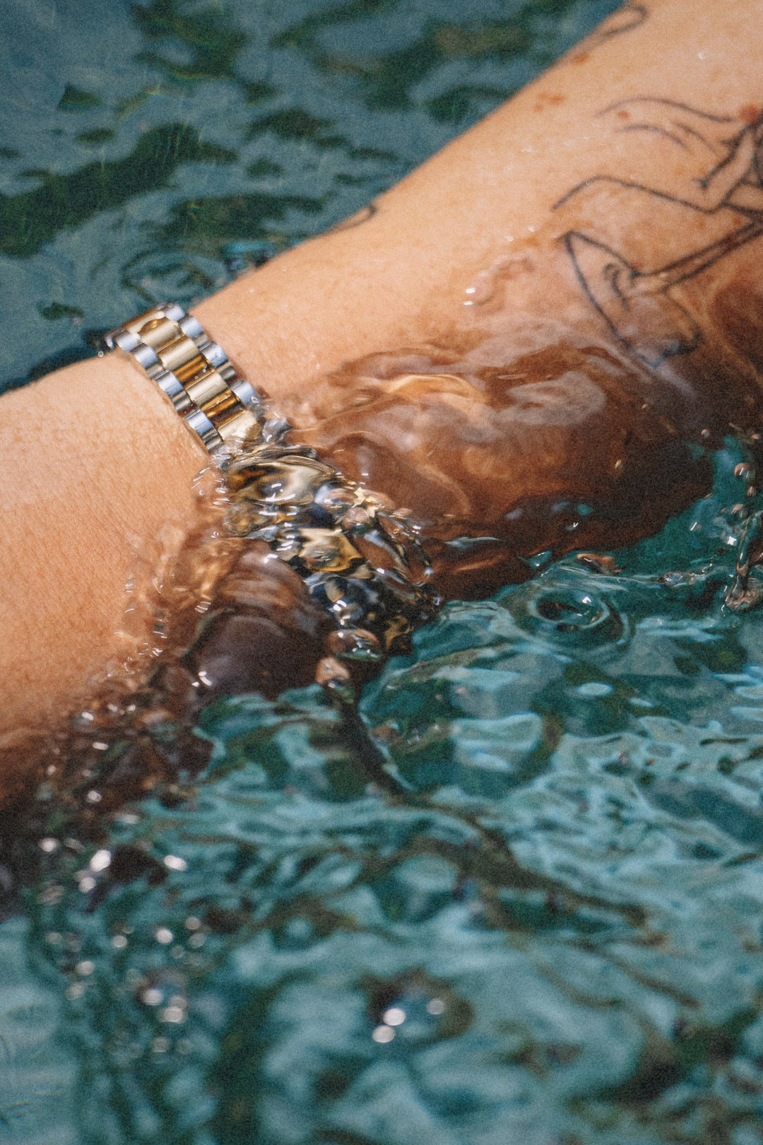 Analog Ava Armband från Alora Avenue fotograferat under vatten – ett vattentåligt och allergivänligt armband i rostfritt stål med gulddetaljer. Perfekt för strandliv, pooldagar och varje tillfälle där stil möter funktion. 