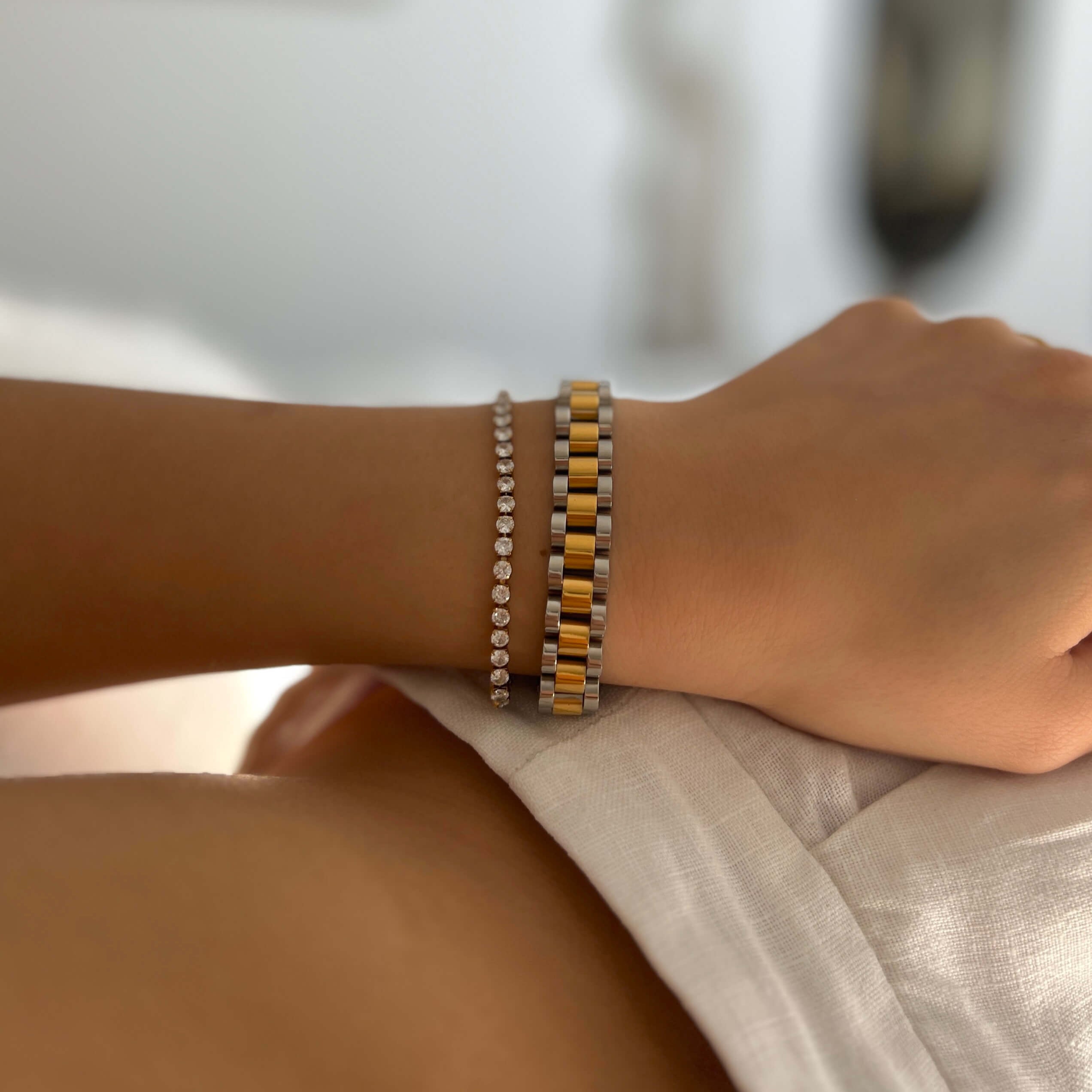 Analog Ava Armband från Alora Avenue i en elegant kombination med gnistrande tennisarmband – en vattentålig och allergivänlig accessoar i guld- och silvertoner. Ett armband som förhöjer känslan av avslappnad lyx, perfekt för både vardag och vilodag.