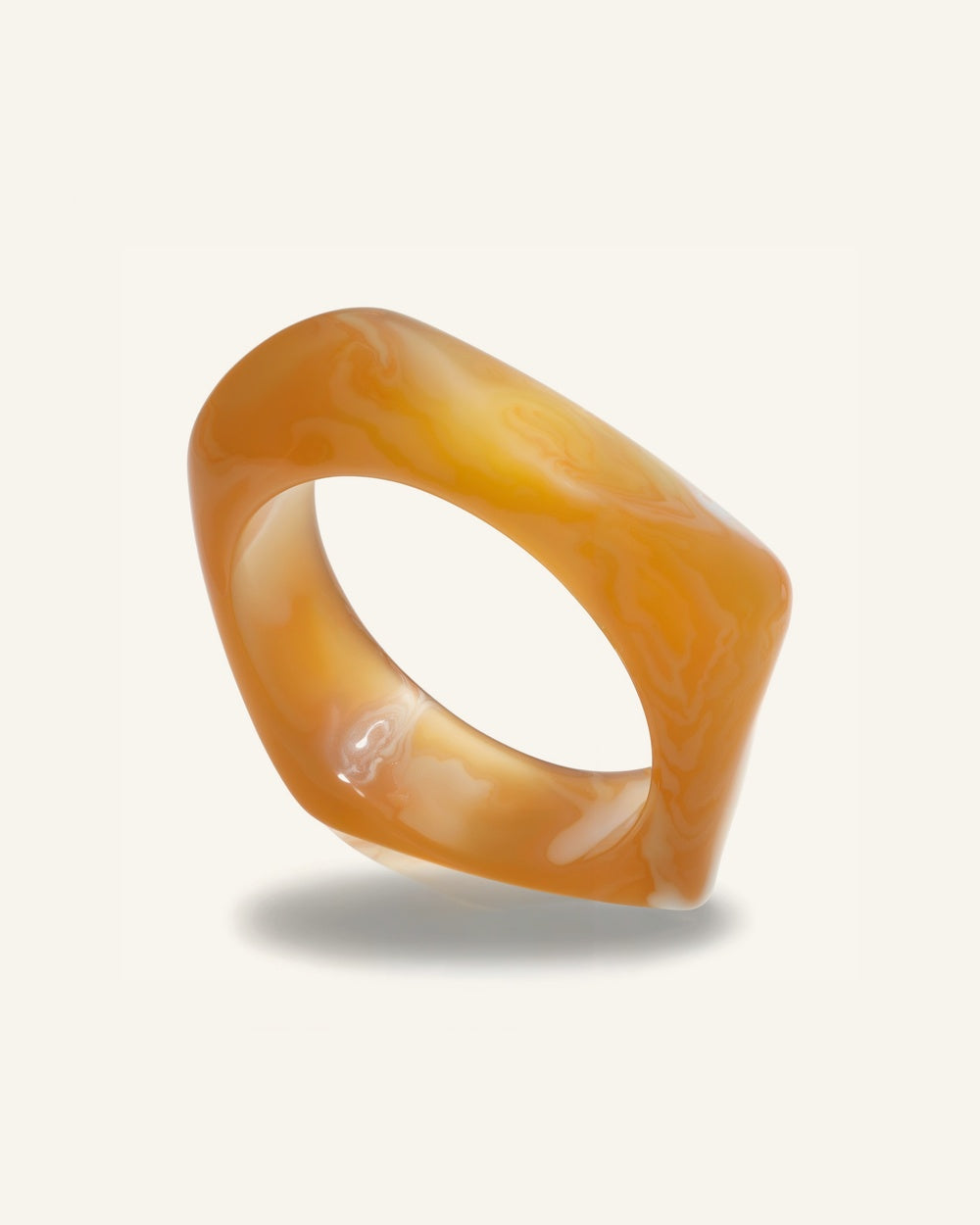 Costa Amber Bangle — Marmorerad amber-akrylbangle i karamellton på beige bakgrund | Alora Avenue