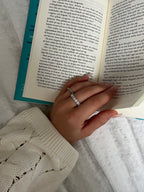 Vackra Filippa Frost Ring på en solkysst hand som bläddrar i en bok. 