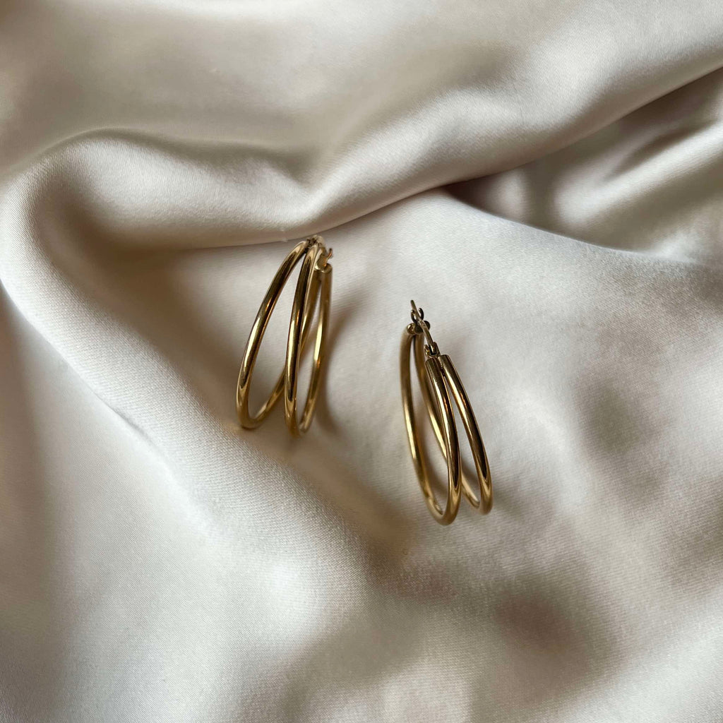 Gemini Cherry Hoops i 18K guldpläterat rostfritt stål. Två hoops per öra för en lekfull och stilren look. Vattentåliga och hållbara.