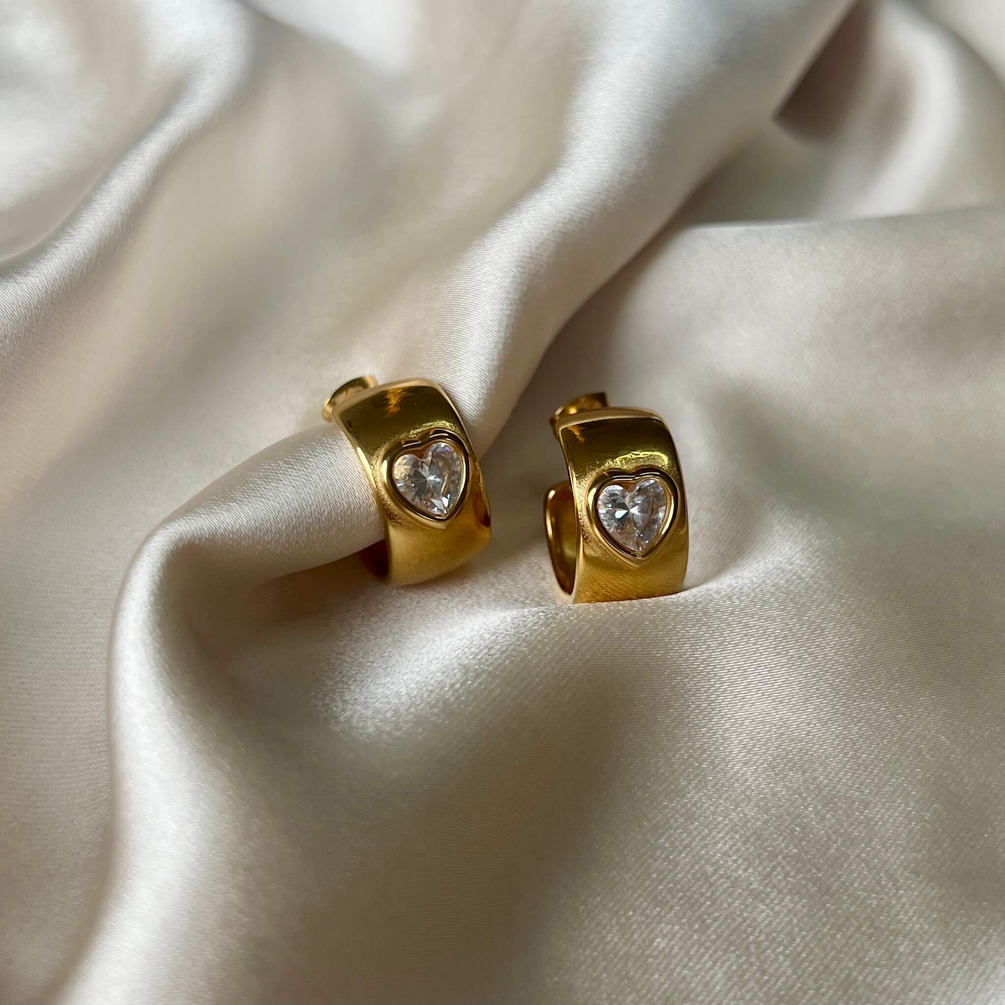 Havanna Heart Earrings – chunky halvhoops i 18K guld med gnistrande zirconia-hjärtan. Romantiska och vattentåliga.