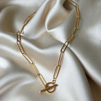 Lana Lotus Necklace – guldfärgad paperclip-kedja med unikt T-lås, elegant design och slitstark PVD-plätering för långvarig glans.