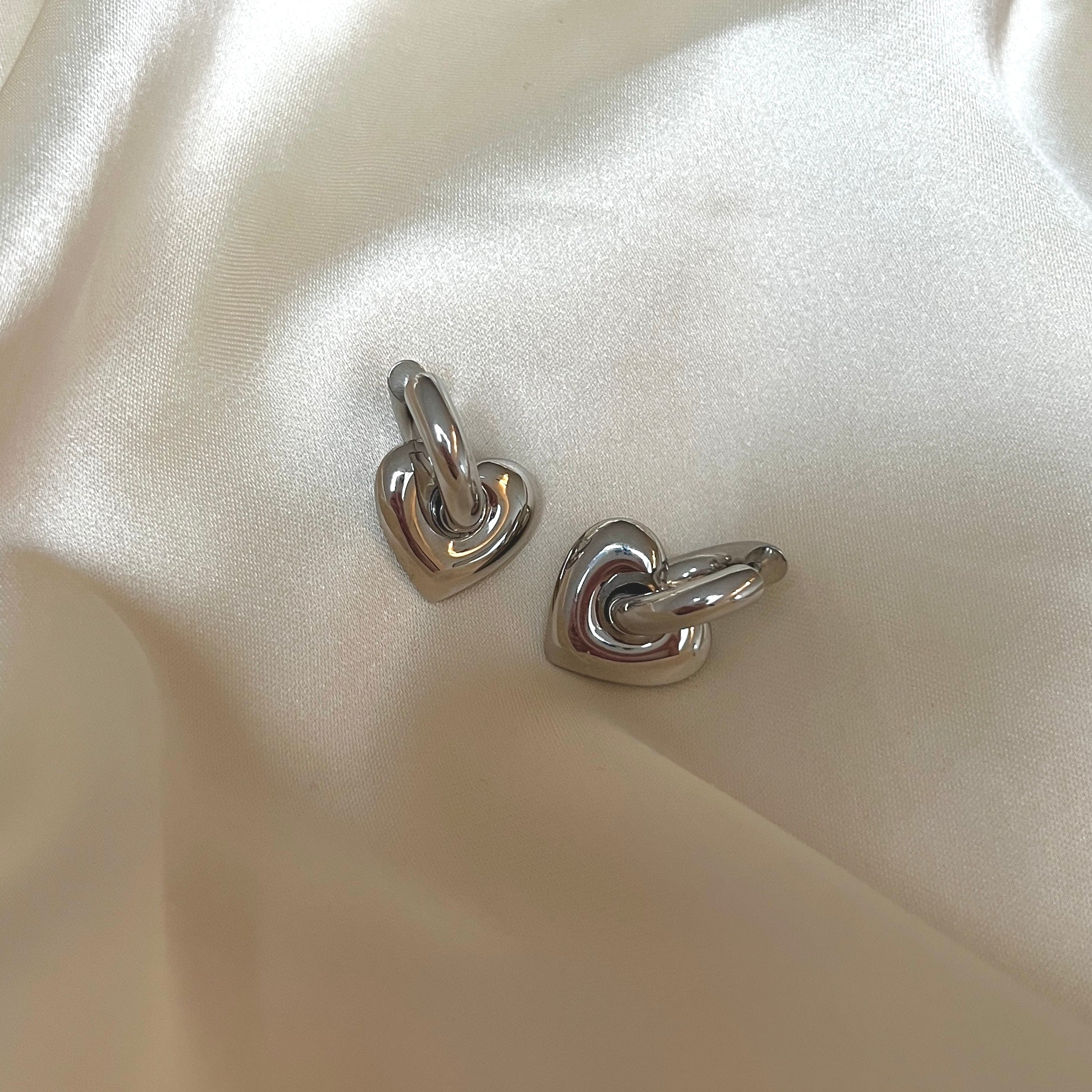Leia Love Loops från Alora Avenue – vattentåliga och allergivänliga örhängen i blankt rostfritt stål med hjärtformade hängen i helsilver. Stilrena hoops med en mjuk, romantisk form – perfekta som vardagsfavorit eller tidlös gåva i minimalistisk design.