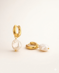 Guldiga hoops med droppformade sötvattenpärlor. Allergivänligt, rostfritt stål med PVD-plätering i 18K guld. Klassisk hoop med en romantisk twist — pärlorna lyfter den från basic till spännande.