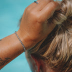 Primrose Belle Bracelet från Alora Avenue bärs vid poolkant – ett elegant, vattentåligt tennisarmband med gnistrande stenar i rostfritt stål. Smycket är både allergivänligt och tåligt nog att bäras i vatten, perfekt för dig som vill kombinera glans och funktion hela sommaren.