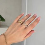Princess Box Ring i guld med gnistrande, infattade rektangulära stenar runt hela ringen. En elegant, vattentålig och allergivänlig statementring från Alora Avenue – perfekt för både vardag och fest.