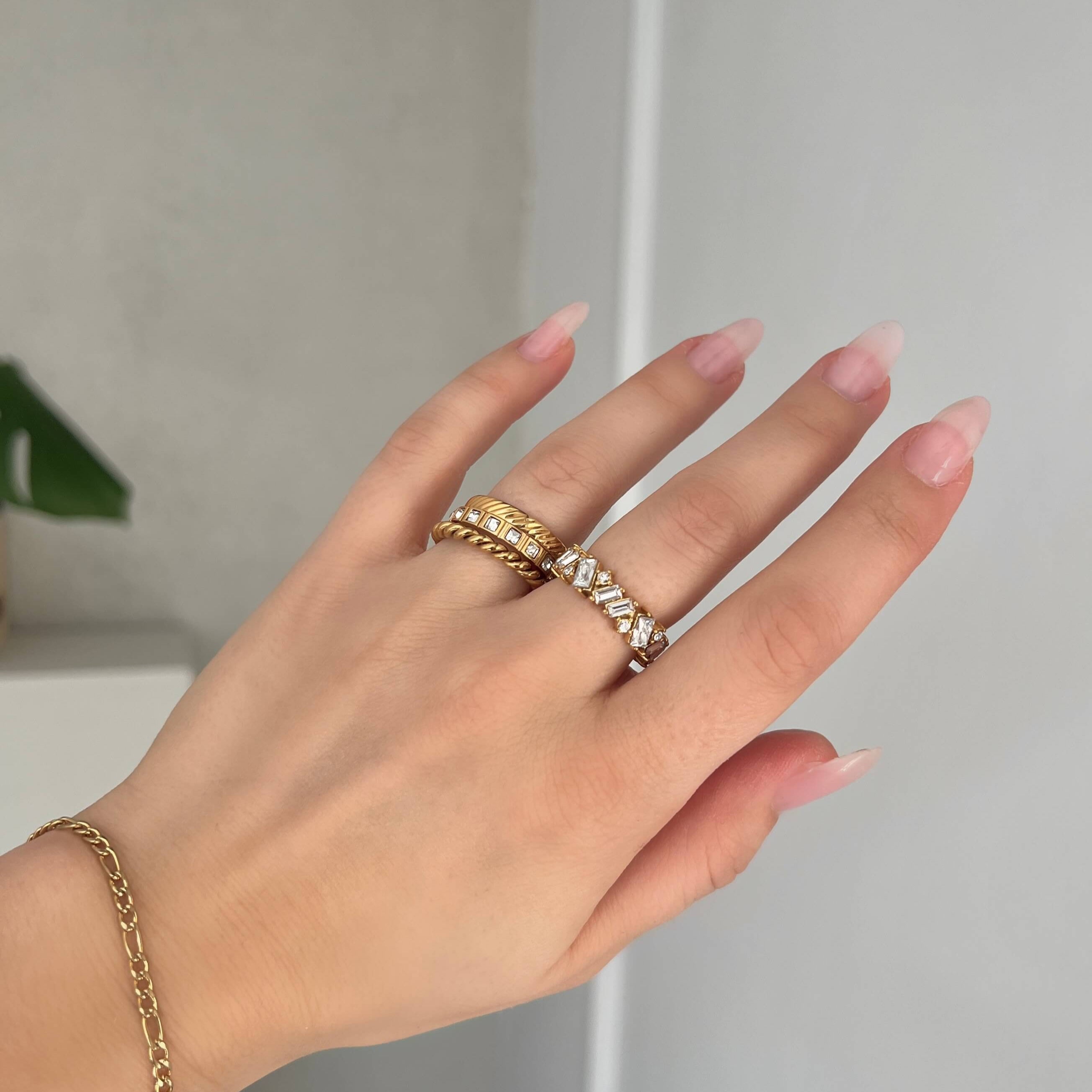 Princess Box Ring i guld med gnistrande, infattade rektangulära stenar runt hela ringen. En elegant, vattentålig och allergivänlig statementring från Alora Avenue – perfekt för både vardag och fest.