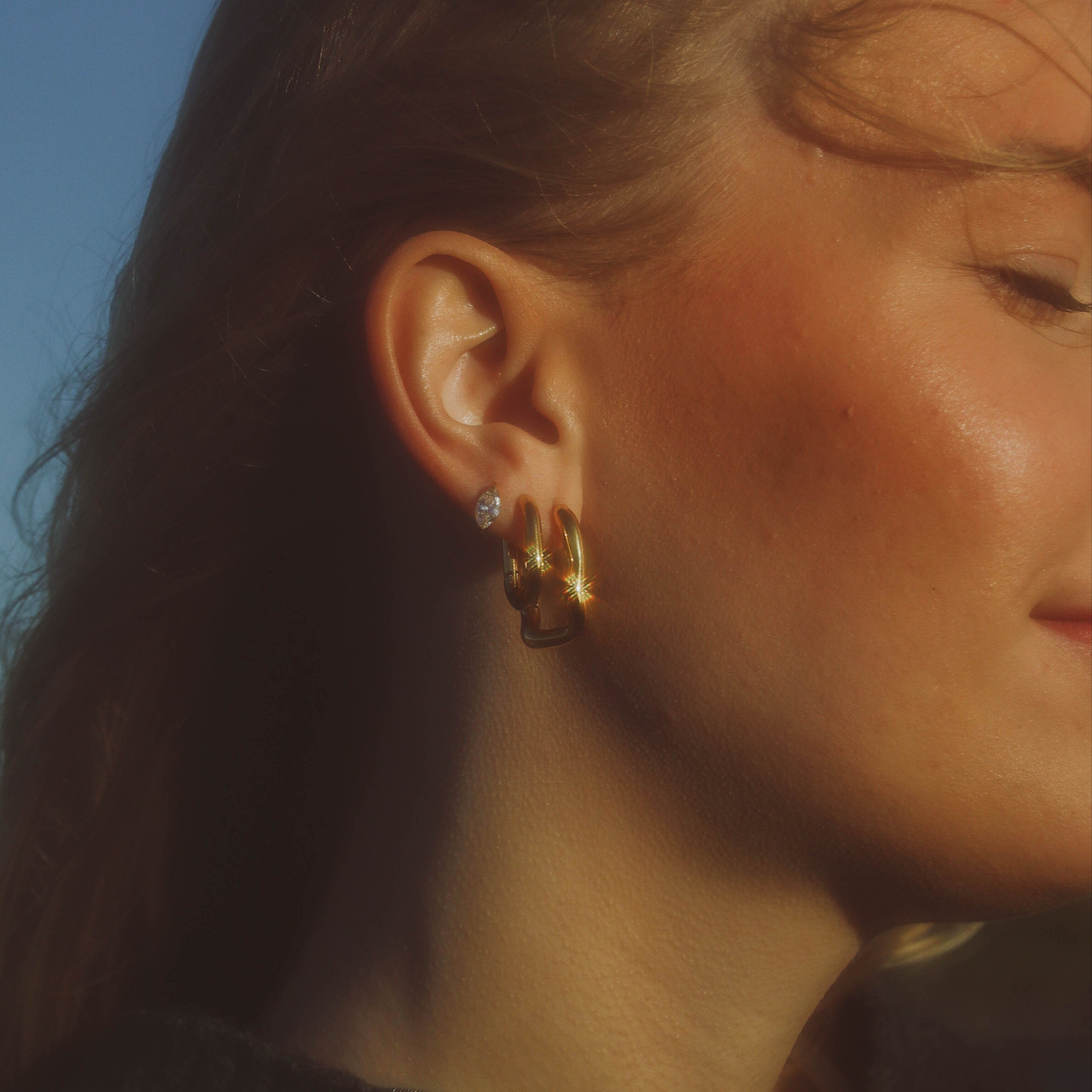 Saint Poppy Hoops i guld från Alora Avenue – eleganta vattentåliga och allergivänliga örhängen i tidlös design, perfekta för både vardag och fest.