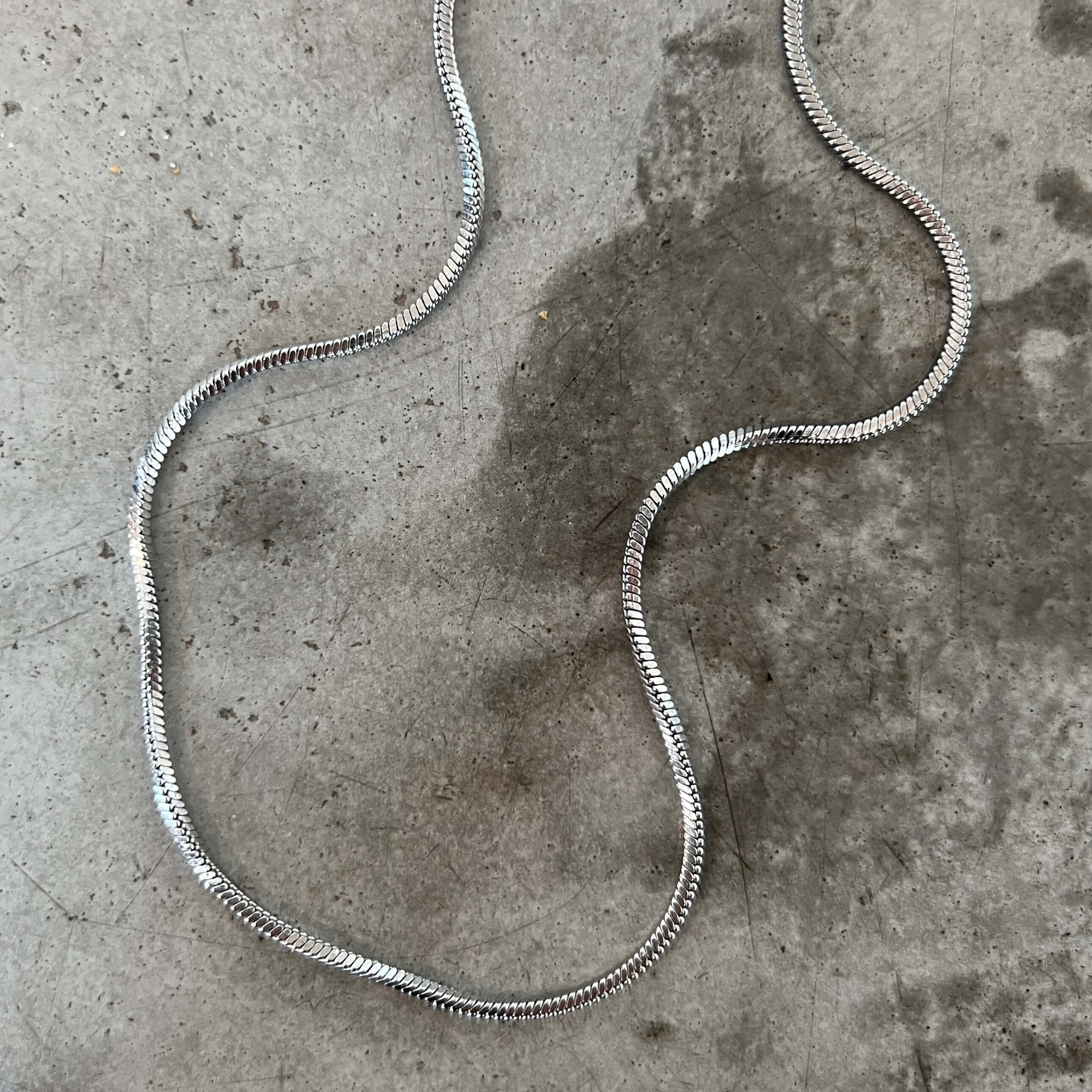 Stella Serpent Necklace – silvrig tjockare ormkedja på 45 cm med kantig design, tillverkad i rostfritt stål och PVD-pläterad för hållbarhet och vattentålighet.