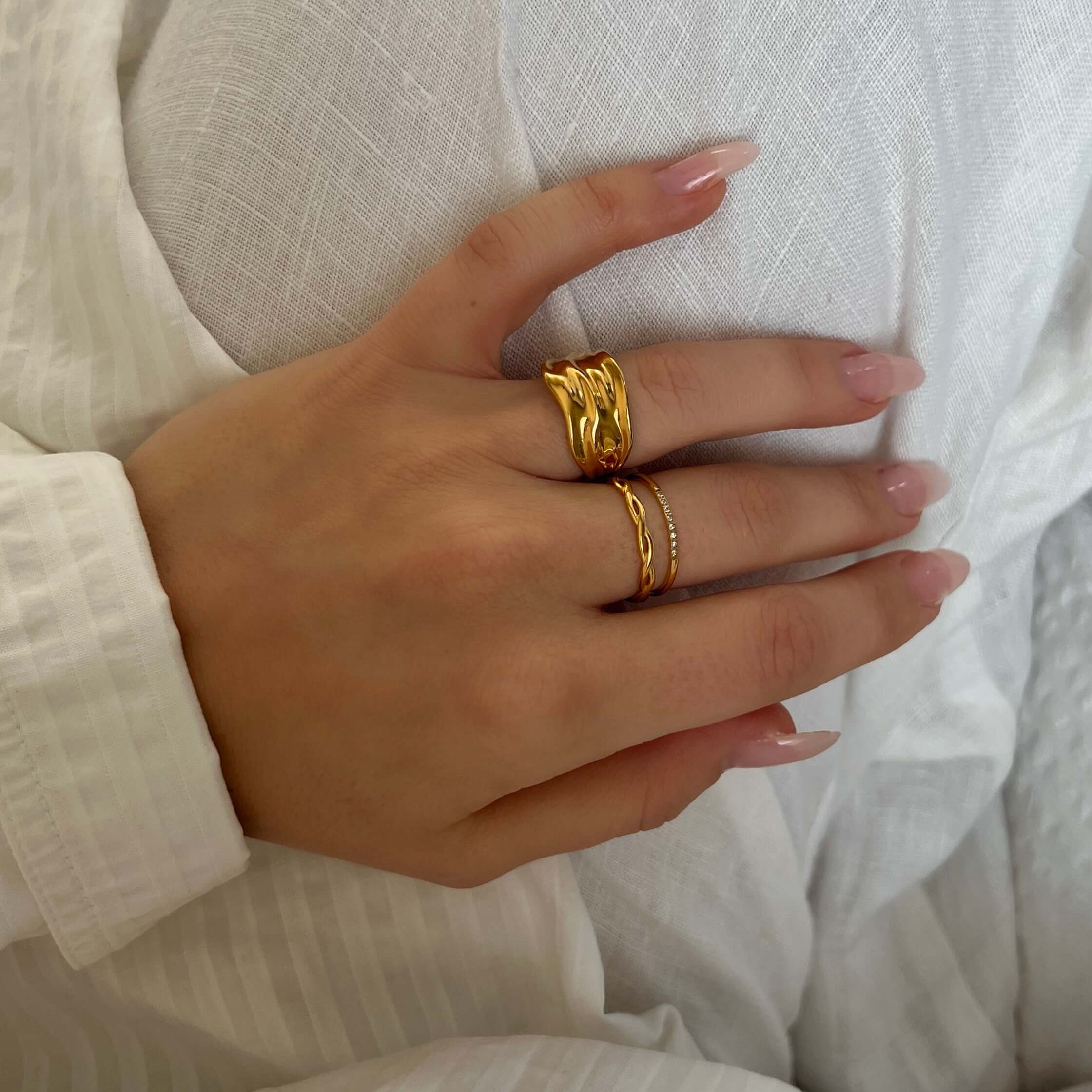 Statementring i guld från Alora Avenue. Wavy Winter Ring har en vågformad, organiskt blank yta och är tillverkad i vattentåligt, allergivänligt rostfritt stål. Ett perfekt smycke för dig som vill leva fritt – utan att kompromissa med stil eller kvalitet.