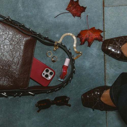 Airy Aurora Necklace i guld placerat i en elegant flatlay med höstlöv, väska och accessoarer. Stilrent och vattentåligt halsband från Alora Avenue – perfekt för vardagslyx.