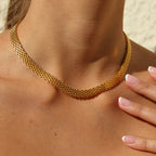 Airy Aurora Necklace i guld runt halsen, fångat i solens ljus. Ett glänsande, elegant halsband från Alora Avenue – vattentåligt och tidlöst i designen.