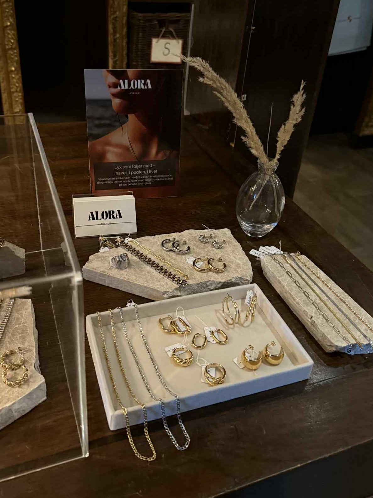 Exklusiv display av Alora Avenue smycken hos återförsäljare Falkenberg Strandbaden – handplockade vattentåliga örhängen, halsband och armband i guld och silver, perfekta för spa, strand och vardagslyx.