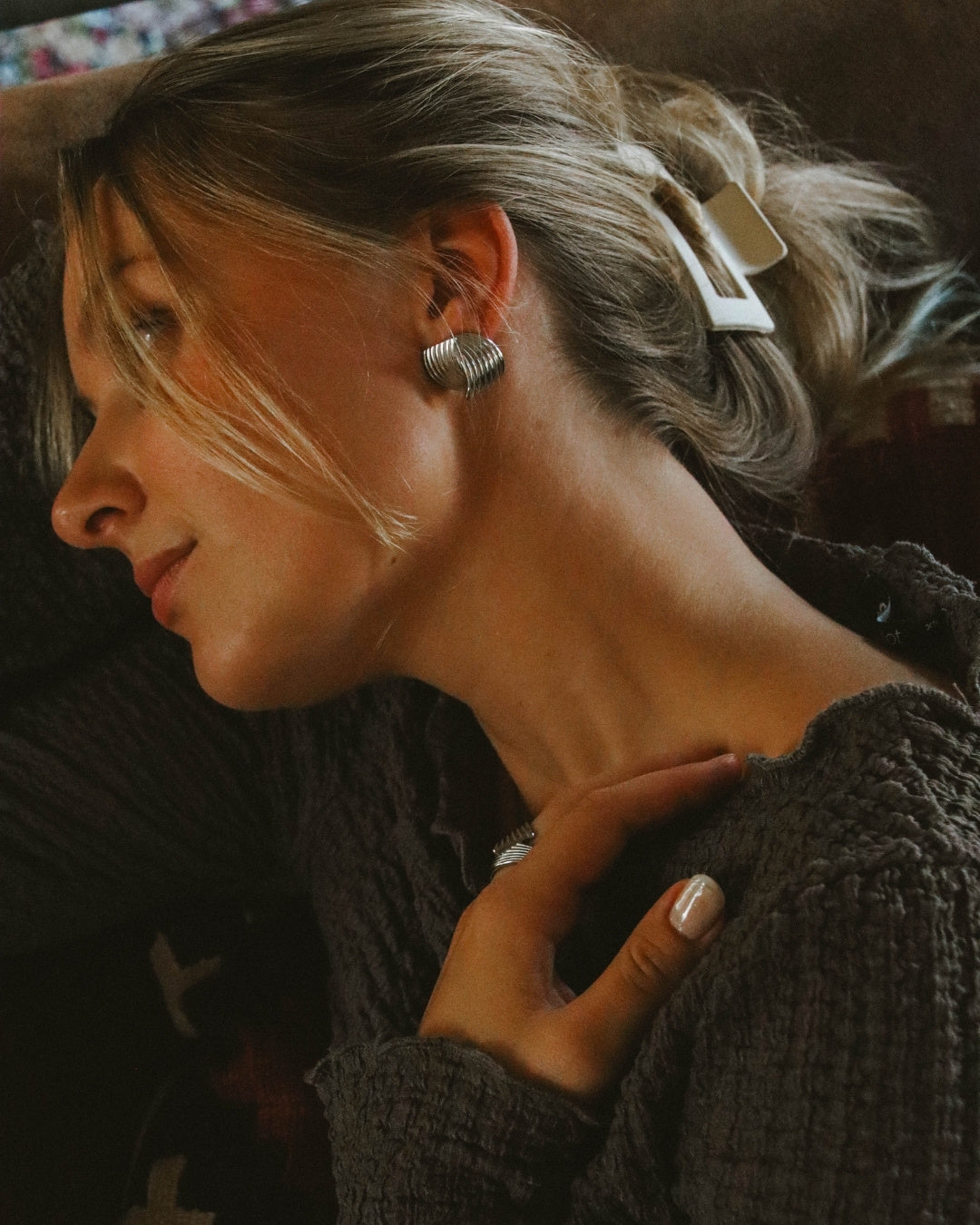 Kvinna bär eleganta guldörhängen i PVD-pläterat rostfritt stål från Alora Avenue – vattentåliga smycken med tidlös design.