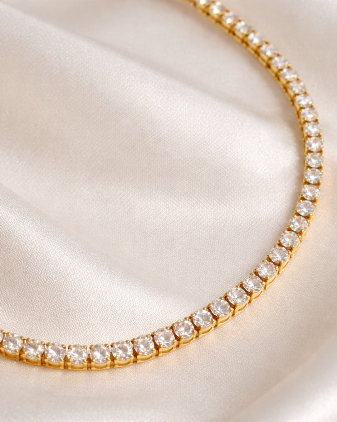 Amara Tennis Necklace i 18K PVD-pläterat guld med vita stenar, vattentåligt halsband i rostfritt stål på ljust silkestyg