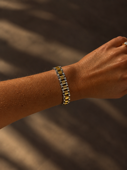 Analog Ava Wristband i guld och silver buret på modell – tvåfärgat länkarmband inspirerat av klassiska klockarmband. Vattentåligt, allergivänligt armband i rostfritt stål från Alora Avenue.