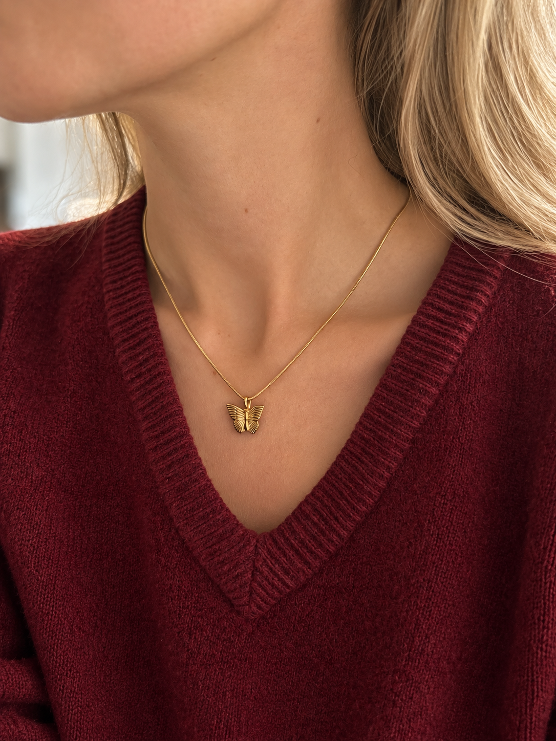 Bea Butterfly Pendant – fjärilsformat hänge i guld på tunn kedja, buret av modell. Vattentåligt guldsmycke från Alora Avenue.
