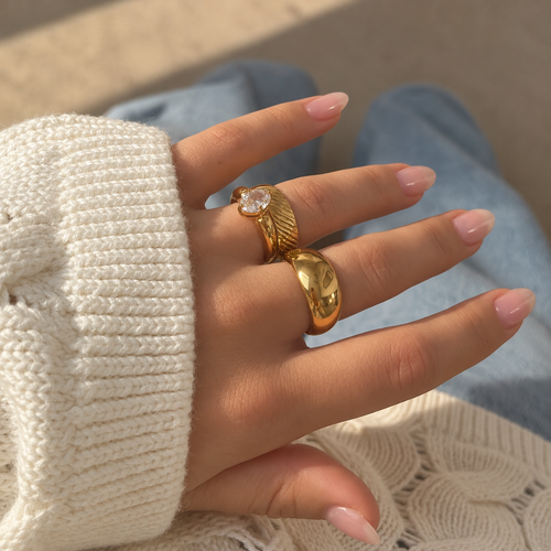Big Blob Ring i guld på modell mot stickad tröja och denim, buren i en ringstack. Vattentålig och allergivänlig chunky ring i rostfritt stål med 18K PVD-guldplätering från Alora Avenue.
