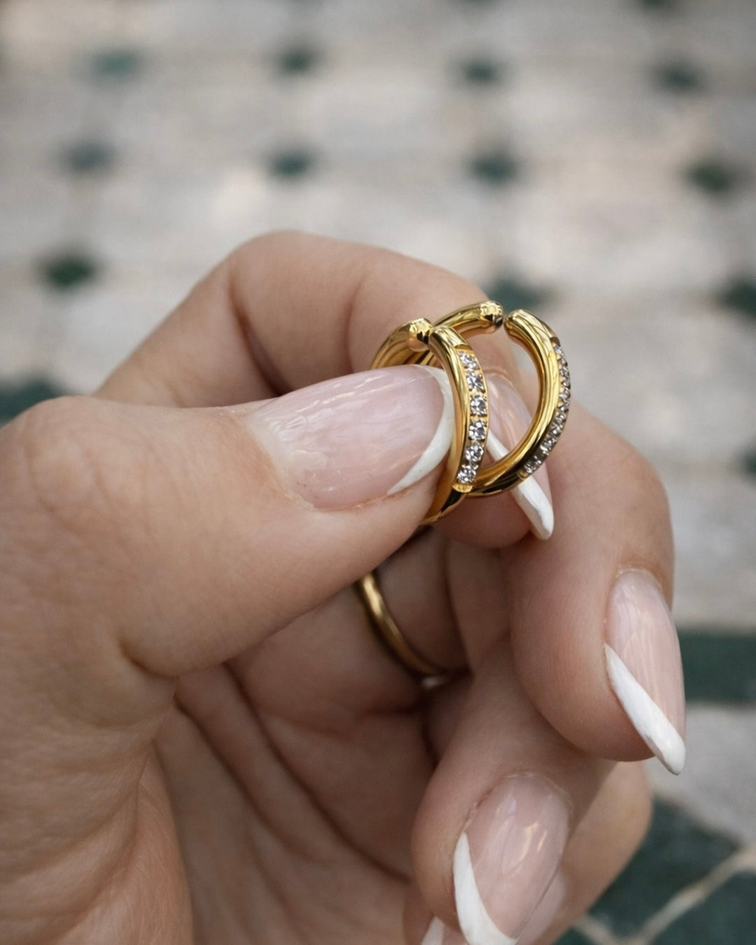 Detaljbild på Cassia Clip Hoop 15 mm – guldiga clip-on örhängen med sex cubic zirkonia-stenar, vattentålig design och bekväm passform som inte klämmer på öronsnibben.