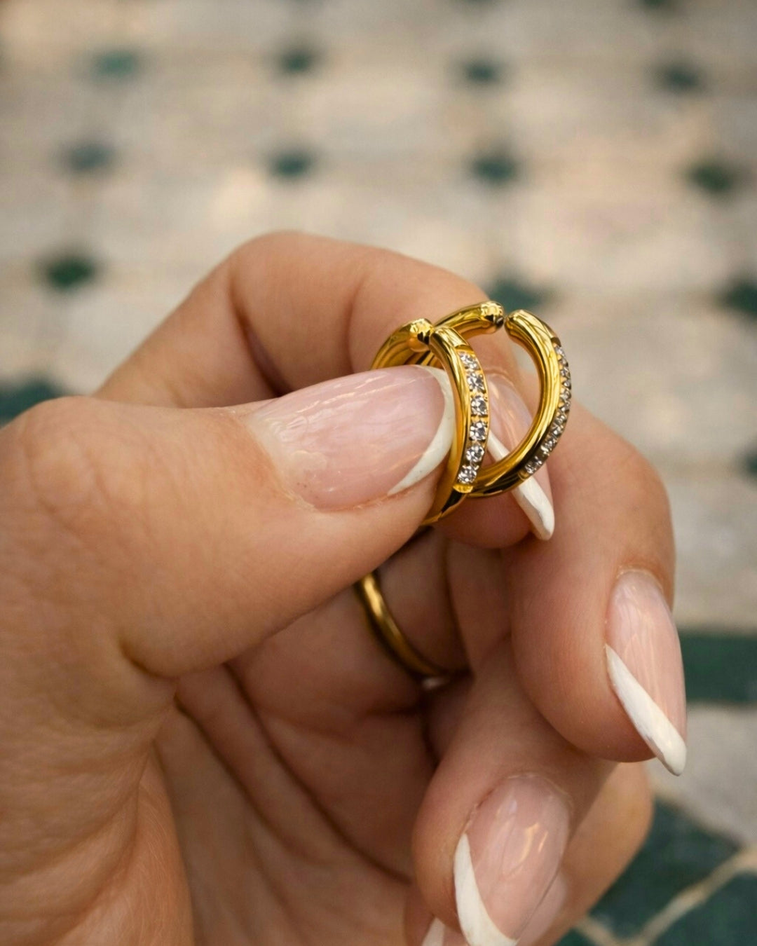 Detaljbild på Cassia Clip Hoop 15 mm – guldiga clip-on örhängen med sex cubic zirkonia-stenar, vattentålig design och bekväm passform som inte klämmer på öronsnibben.