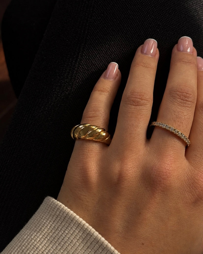 Guldringar i ringstack på modell – Classic Croissant Ring med flätat croissantmönster och Twinkle Tara Ring med cubic zirconia. Vattentåliga, allergivänliga ringar från Alora Avenue.