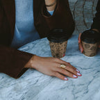 Dawn Clip Bracelet i guld på handled, stylat med kaffekopp på marmorbord. Tidlöst armband med klipplänkar från Alora Avenue – elegant, vattentåligt och hållbart.