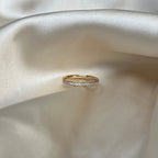 Elara Glow Ring i guld med gnistrande stenar längs halva ringen, fotograferad på ljus sidenbakgrund. Tidlös, vattentålig och allergivänlig ring från Alora Avenue.
