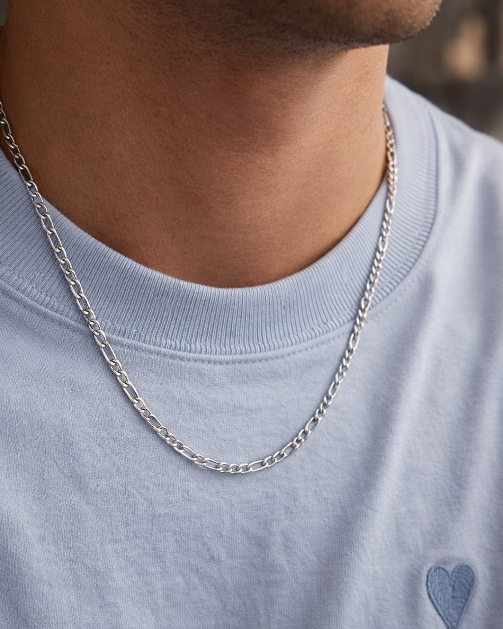 Close-up på man som bär Fernando Figaro Necklace – en klassisk silverfärgad figarolänk i allergivänligt rostfritt stål, 4 mm bred och vattentålig design.