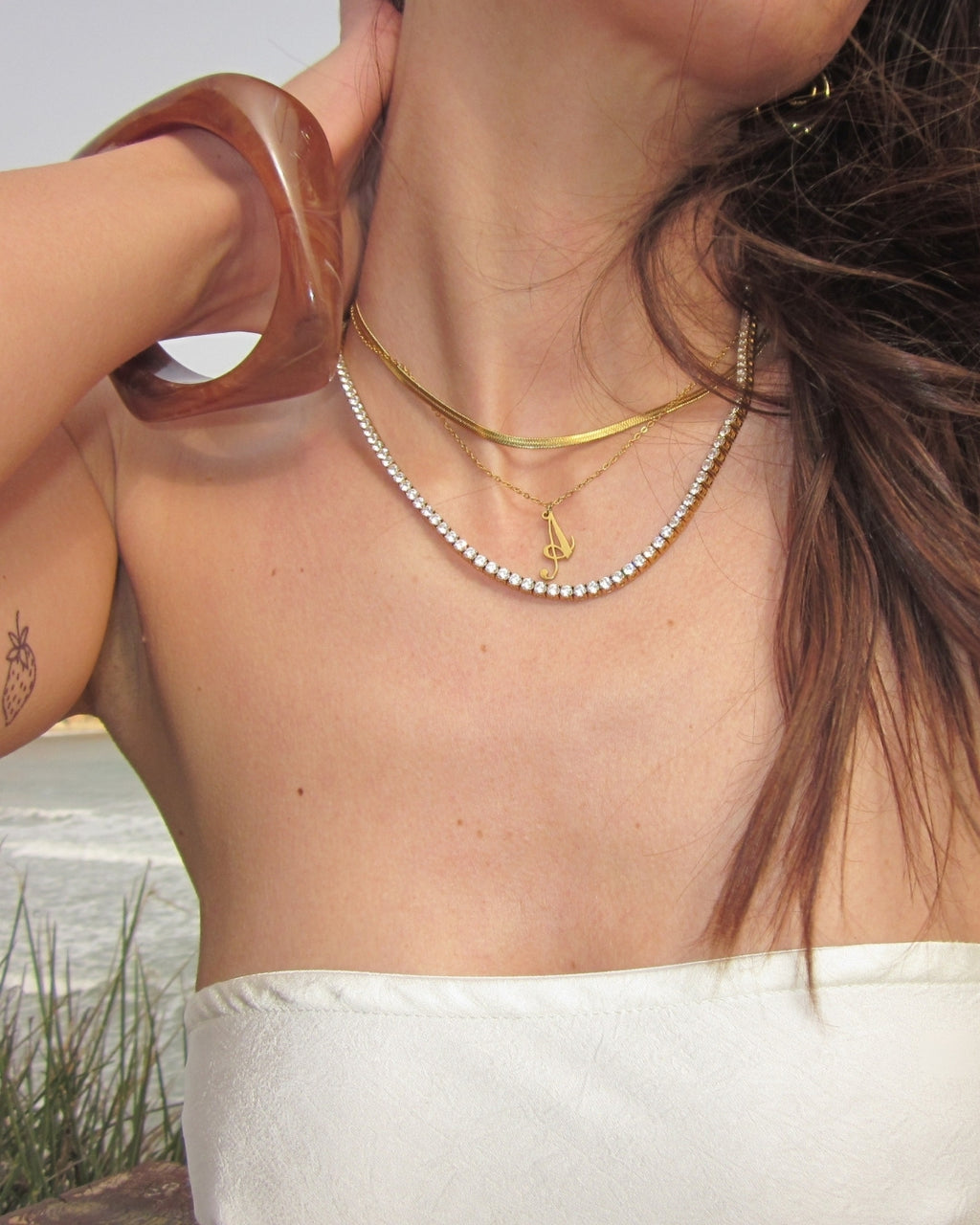 Costa Cocoa Bangle — Halsband-layering med guldkedjor och Costa-bangle vid strand | Alora Avenue