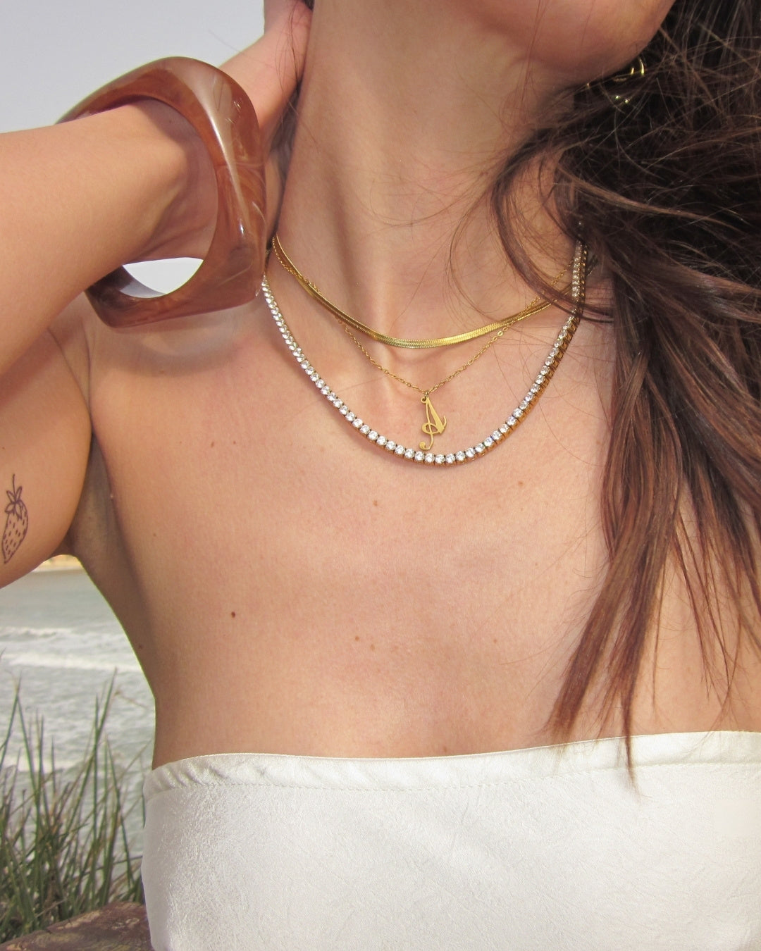 Costa Cocoa Bangle — Halsband-layering med guldkedjor och Costa-bangle vid strand | Alora Avenue
