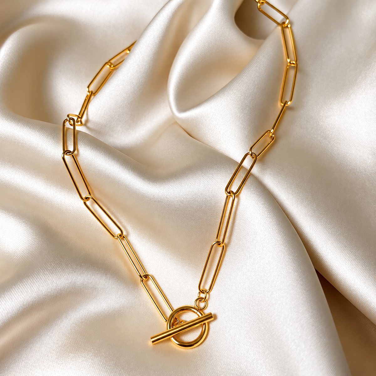 Lana Lotus Necklace i guld fotograferat på ljust silkestyg. Vattentåligt och allergivänligt halsband i rostfritt stål med 18K PVD-guldplätering från Alora Avenue.