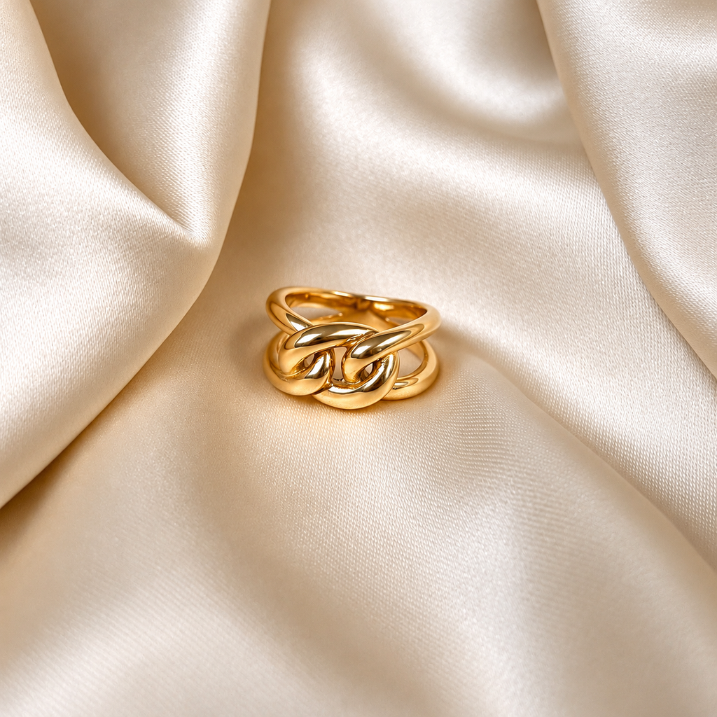 Livia Loop Ring i guld fotograferad på ljust silkestyg. Vattentåligt och allergivänligt smycke i rostfritt stål med 18K PVD-guldplätering från Alora Avenue.