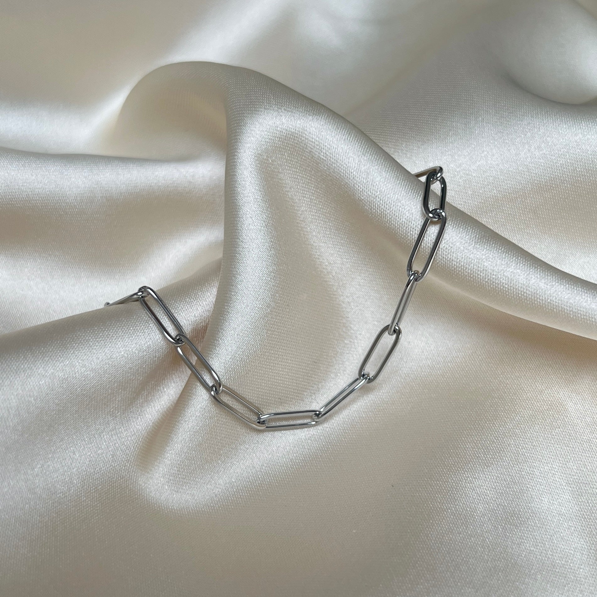 Lucid Clip Bracelet – elegant silverfärgat armband med trendiga avlånga länkar, stilrent fotat mot krämvit satin för Alora Avenue
