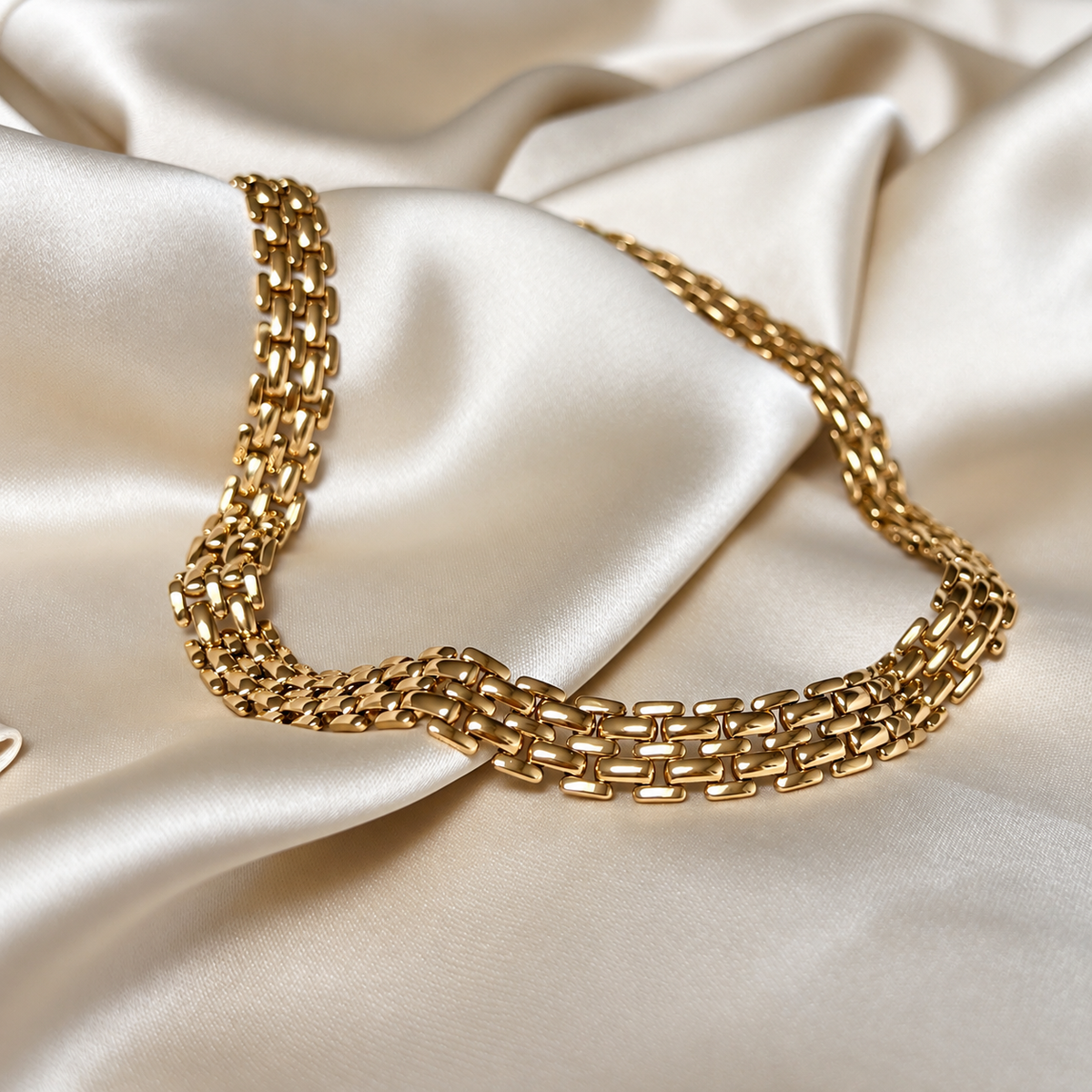 Mont Magnolia Necklace i guld fotograferat på ljust silkestyg. Vattentåligt och allergivänligt halsband i rostfritt stål med 18K PVD-guldplätering från Alora Avenue.