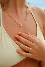 Närbild på Polly Pearl Necklace från Alora Avenue – ett elegant guldhalsband med sötvattenspärla, perfekt för stranddagar och vardagslyx. Smycket är vattenresistent och allergivänligt.