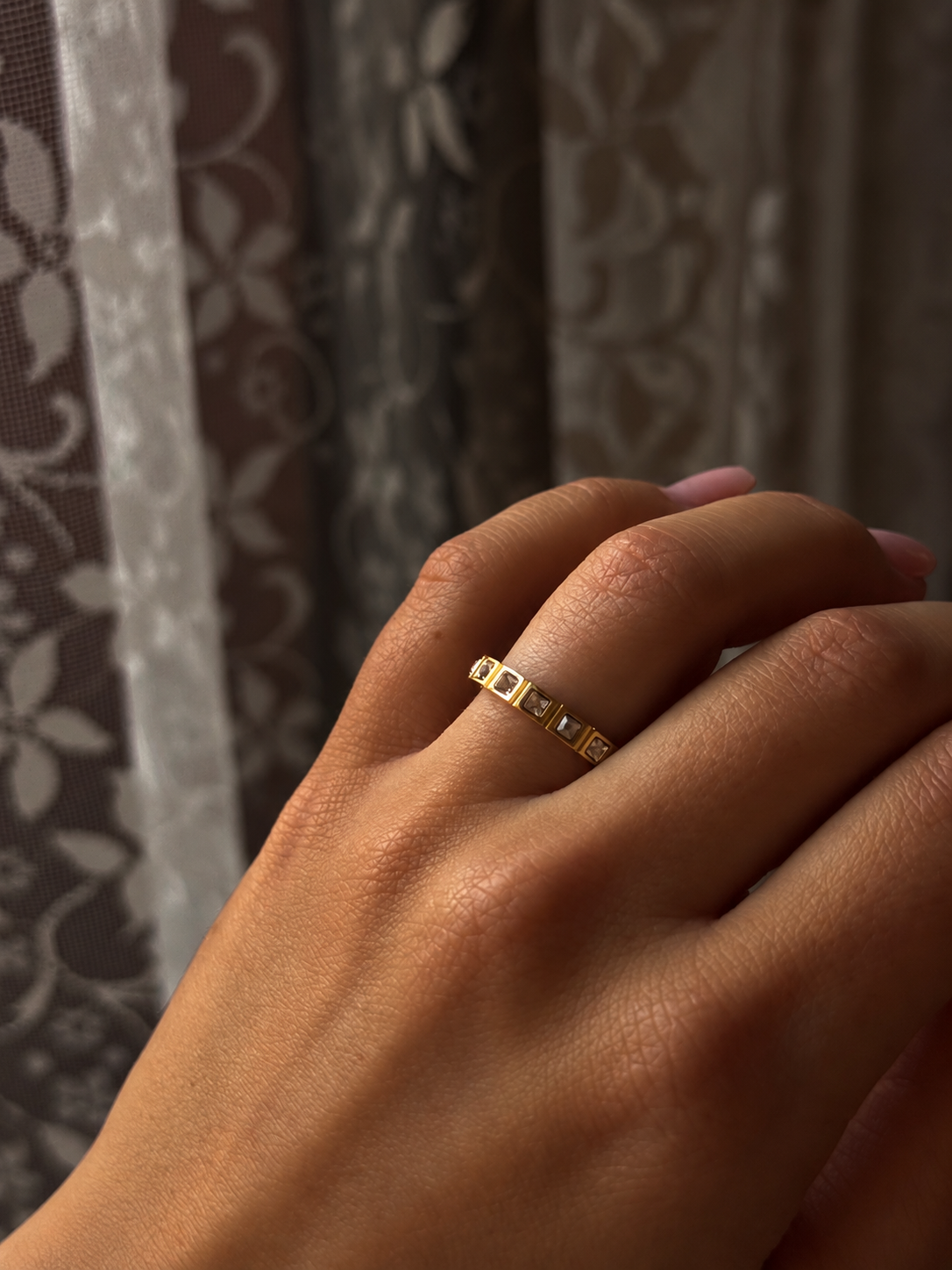 Princess Box Ring i guld buren på modell – smal ring med fyrkantiga cubic zirconia-stenar i infattade boxar runt hela ringen. Vattentålig ring i rostfritt stål med 18K guldplätering från Alora Avenue.