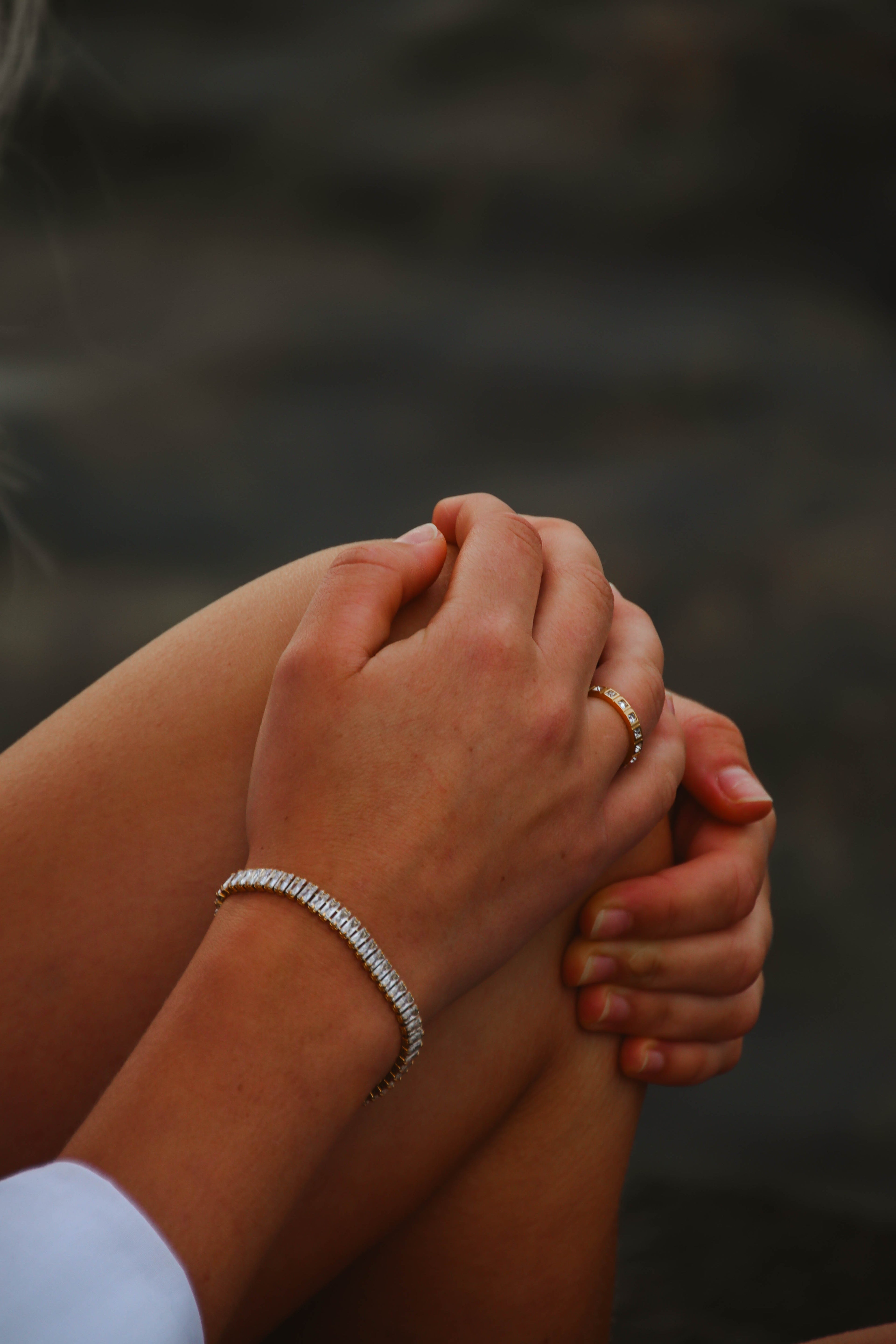 Närbild på Santiago Sunstone Bracelet från Alora Avenue – ett gnistrande guldarmband med baguetteslipade stenar, stylat vid havet tillsammans med en guldring.