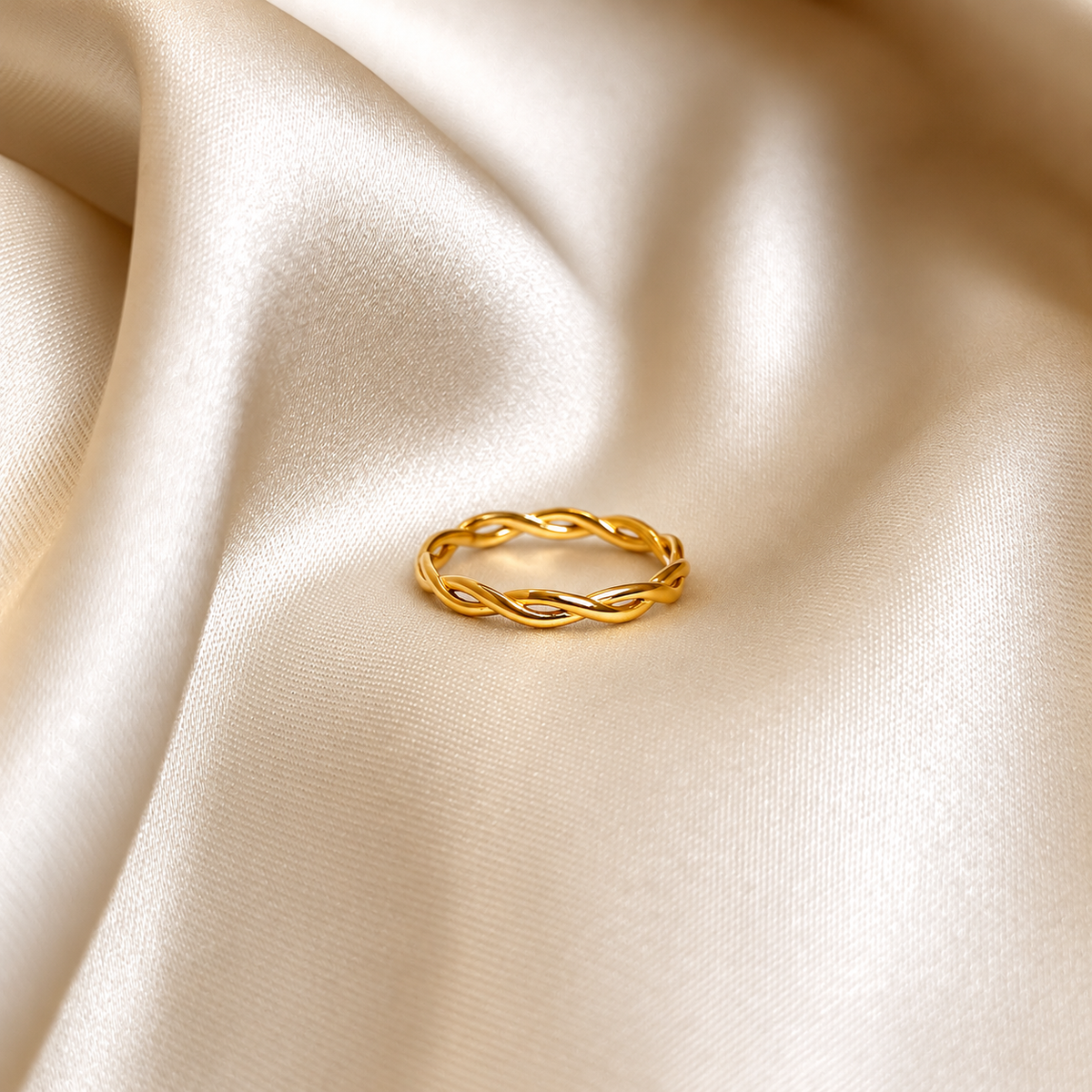 Serpentine Sea Ring i guld fotograferad på ljust silkestyg. Vattentåligt och allergivänligt smycke i rostfritt stål med 18K PVD-guldplätering från Alora Avenue.