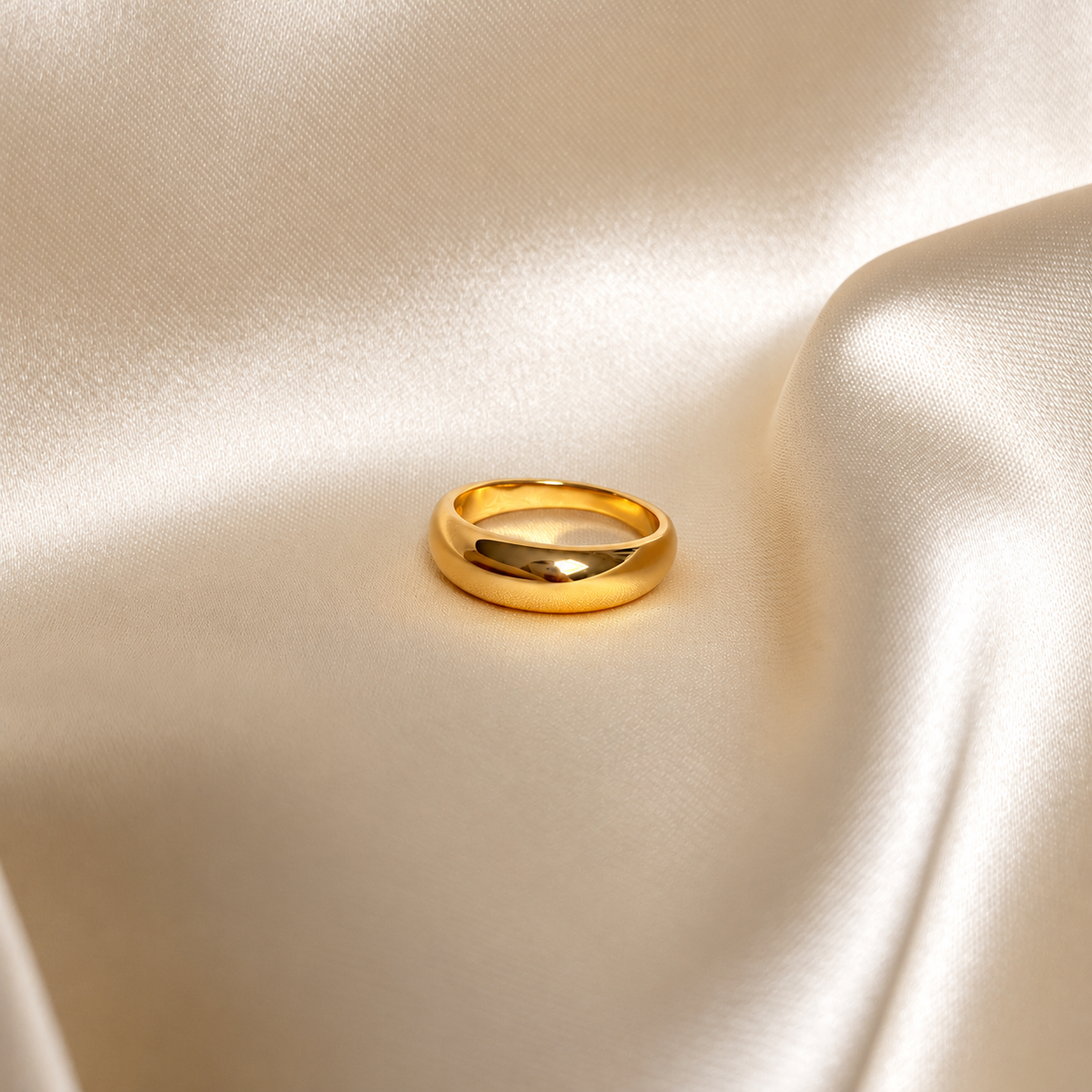 Sleek Storm Ring i guld fotograferad på ljust silkestyg. Vattentålig och allergivänlig ring i rostfritt stål med 18K PVD-guldplätering från Alora Avenue.